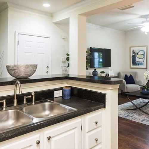 a kitchen with a black counter and a living room