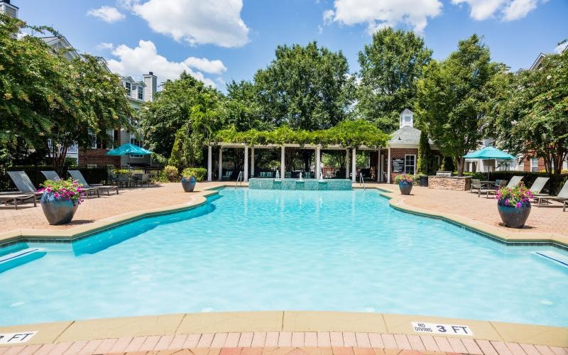a swimming pool with trees and a building in the background